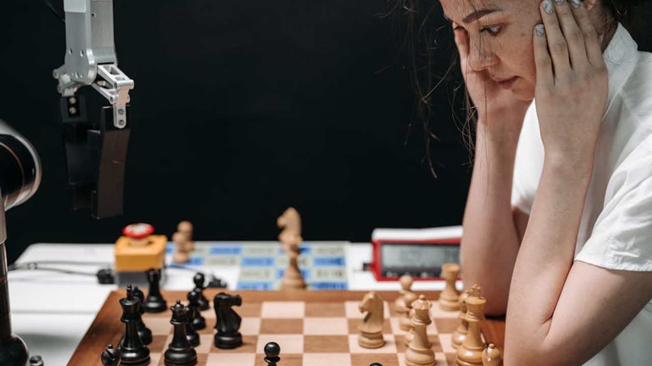 A gaming coach reviewing gameplay footage with a student, pointing at the screen with strategic notes