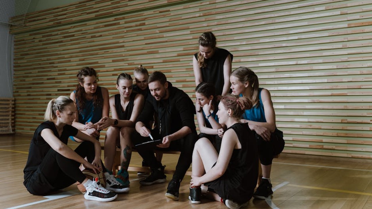 Esports team with their coach in a huddle, strategizing before a match